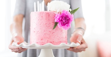 hands holding a pink cake on a platter